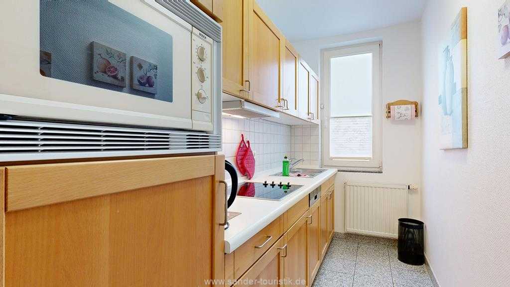 Räumlich abgetrennte gut ausgestattete Küchenzeile mit Spülmaschine